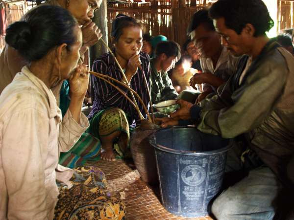 Villagers drinking fermented ‘jar liquor’ through long bamboo straws, at a festive village occasion.